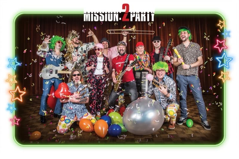 Mission:2Party Bandfoto im Party-Look — bunte Kostüme und Perücken zwischen Luftballons und Konfetti